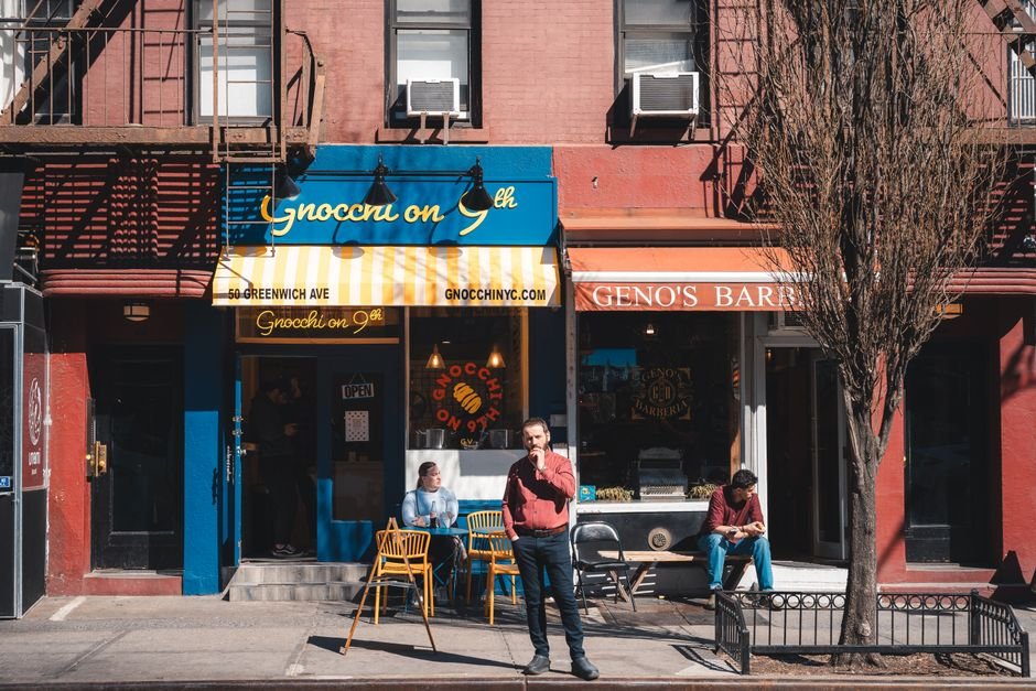 Daytime view of people outside Gnocchi on 9th and Geno's Barbershop in Greenwich Village, NYC.