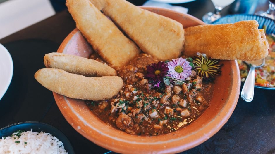 Flavorful traditional dish with breaded sides and vibrant garnish in a rustic bowl.