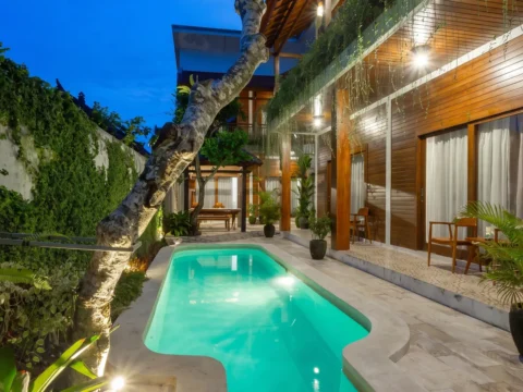 Pool and guest rooms at Paisa Ubud lit up in the evening